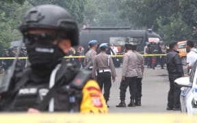 Police officers stand guard on a road near the scene suicide bombing attack in Bandung, Indonesia.