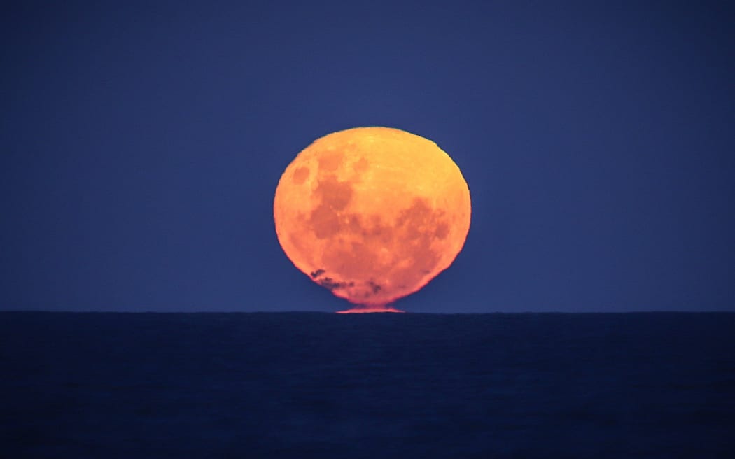 The Strawberry Moon, the full moon of the month of June, rises over the ocean on Narrawallee Beach, near Mollymook on the South Coast of New South Wales on June 6, 2020.