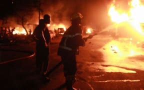 This video frame grab taken from AFPTV footage shows firefighters working to put out a fire at a petrol station early on November 6, 2021 in Freetown, Sierra Leone, following a massive explosion that has killed at least 92 people.
