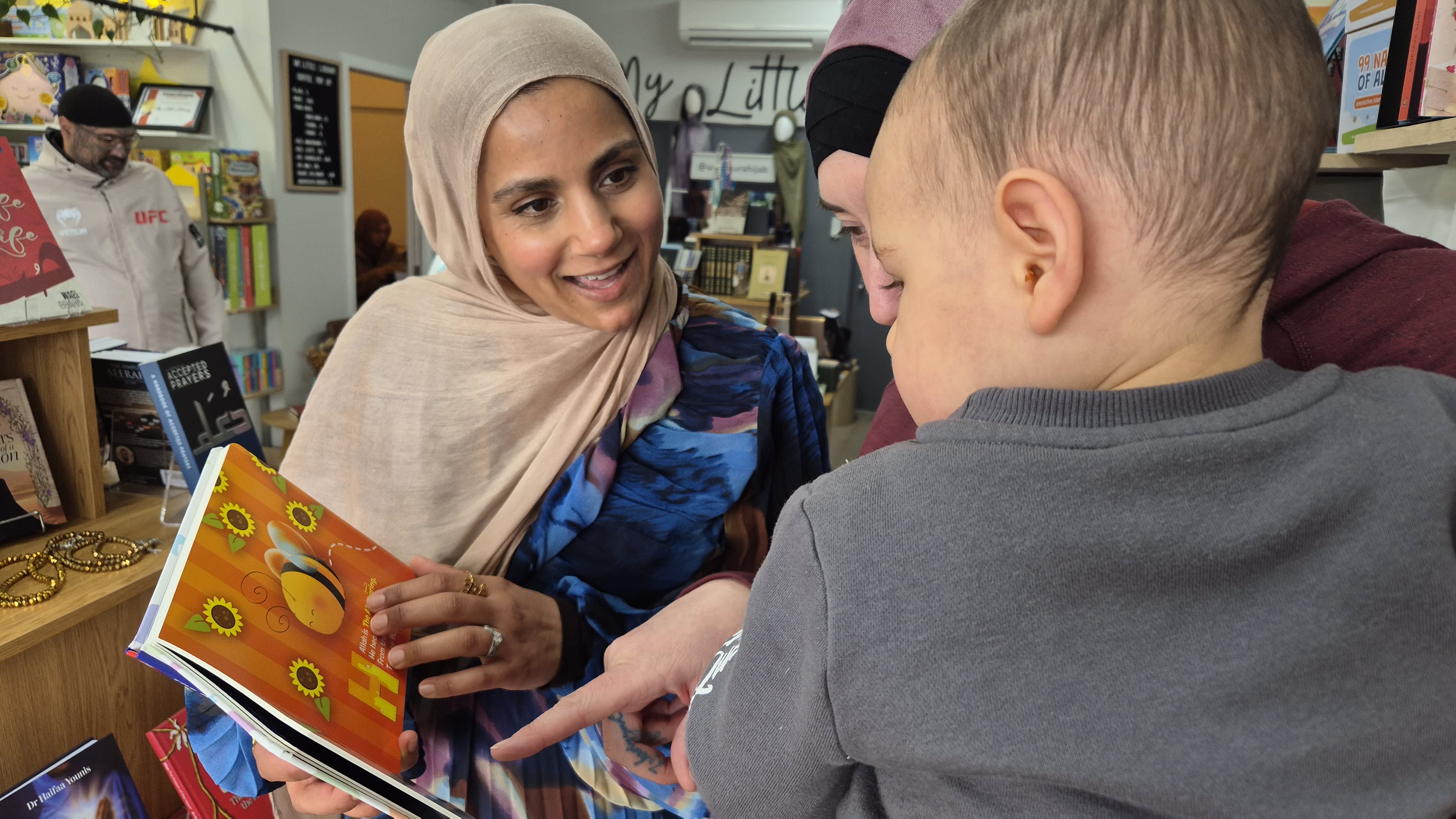 Saadiyah Musa and Leaza Karena show a children's books to Leaza's son Zakariah.