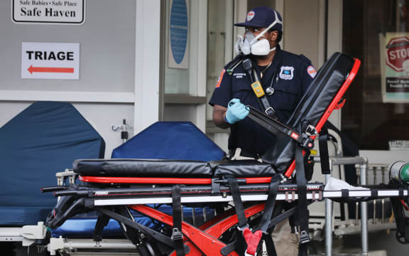 Medical workers in New York take in patients at a special coronavirus area at Maimonides Medical Center as the US surpasses 100,000 fatalities from Covid-19.