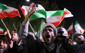 Demonstrators wave Iran's flag and Palestinian flags as they gather in front of the British Embassy in Tehran on April 14, 2024, after Iran launched a drone and missile attack on Israel. Iran's Revolutionary Guards confirmed early April 14, 2024 that a drone and missile attack was under way against Israel in retaliation for a deadly April 1 drone strike on its Damascus consulate. (Photo by ATTA KENARE / AFP)