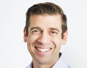 Dr Justin Coulson smiling in front of a white background