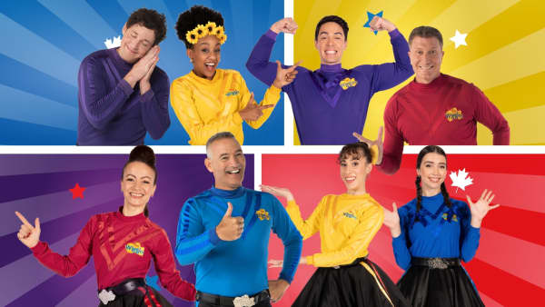 EIght smiling people dressed in colourful tops.