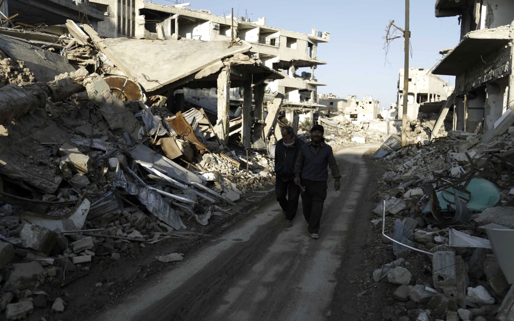 Syrian men walk along a street damaged by shelling in the neighbourhood of Jobar, on the eastern outskirts of the capital Damascus.