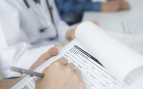 Doctor, nurse of other health worker filling out medical form