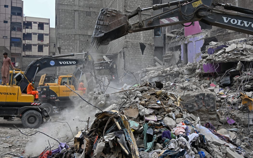 Rescue workers conduct a search operation amid the debris of a collapsed residential building in Karachi on July 5, 2025. Rescue teams pulled more bodies from the rubble of a five-storey building collapse in Pakistan overnight, taking the toll on July 5 to 14 as the recovery operation continued for a second day. (Photo by Rizwan TABASSUM / AFP)
