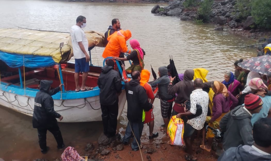 taken on July 23, 2021 shows National Disaster Response Force (NDRF) personnel rescuing stranded villagers from the low lying areas  in Ambewadi of Kolhapur district of Maharashtra.