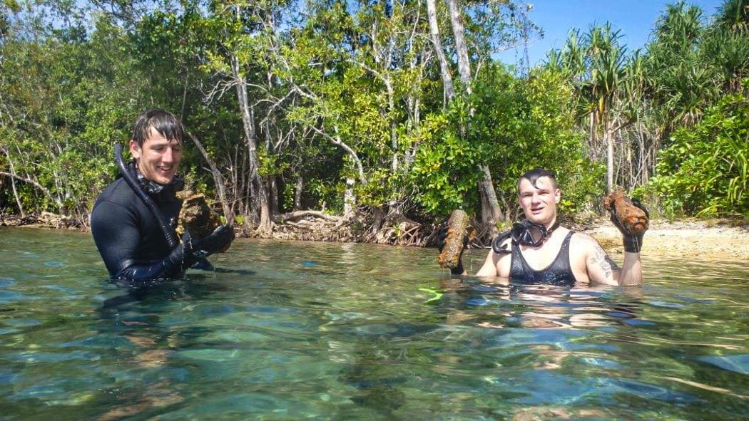 Divers with recovered unexploded ordnance