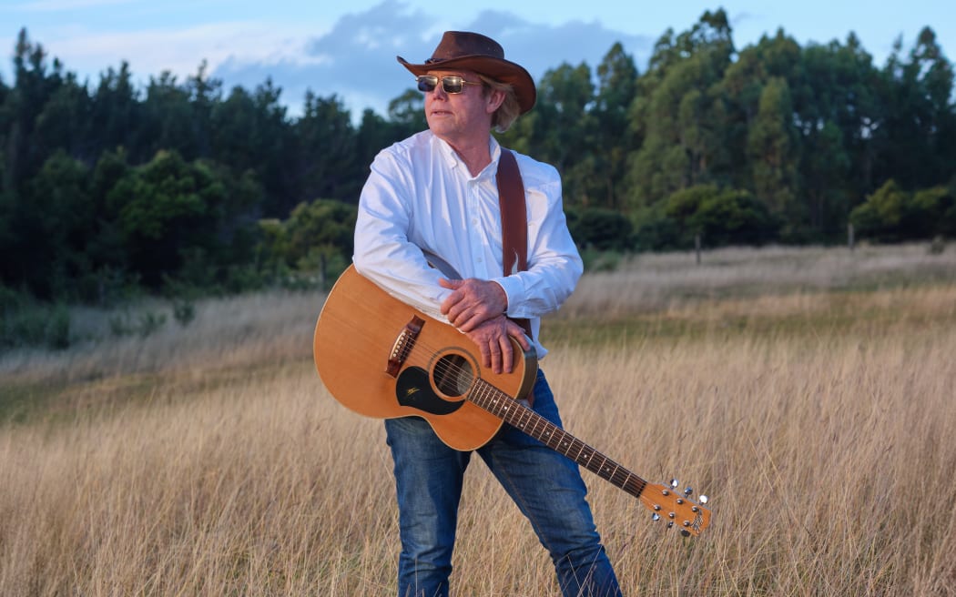 Merv Pinny in a paddock with his guitar