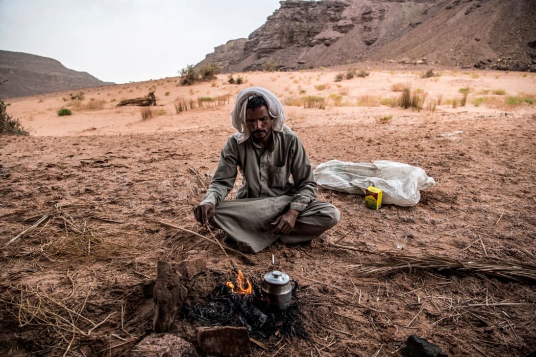 Ibrahim Musalam, a 28-year-old Egyptian Bedouin desert guide, stokes a fire as he prepares tea in the Abu Sour valley, near the coastal town of Abu Zenima in South Sinai governorate, on March 30, 2019. (Photo by Khaled DESOUKI / AFP)