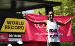 Ethiopia's Tigst Assefa poses after crossing the line to win the women's race at the 2025 London Marathon in central London on April 27, 2025. Ethiopia's Tigst Assefa made up for her second spot last year to coast home in the women's London Marathon in a world record time of 2hr 15min 50sec on Sunday. (Photo by JUSTIN TALLIS / AFP) / “RESTRICTED TO EDITORIAL USE - SPONSORSHIP OF CONTENT SUBJECT TO LMEL AGREEMENT”.