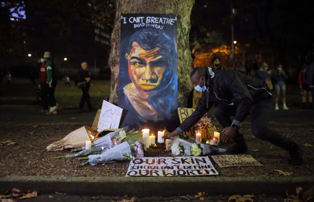 SYDNEY, AUSTRALIA - JUNE 6: A man places a candle at a vigil with a portrait of David Dungay during a protest against Aboriginal deaths in custody in Sydney, Australia on June 6, 2020.
