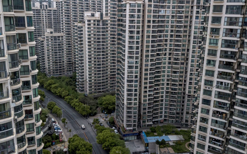 A road cleaning vehicle drives along a street between residential high rise buildings in downtown Shanghai.