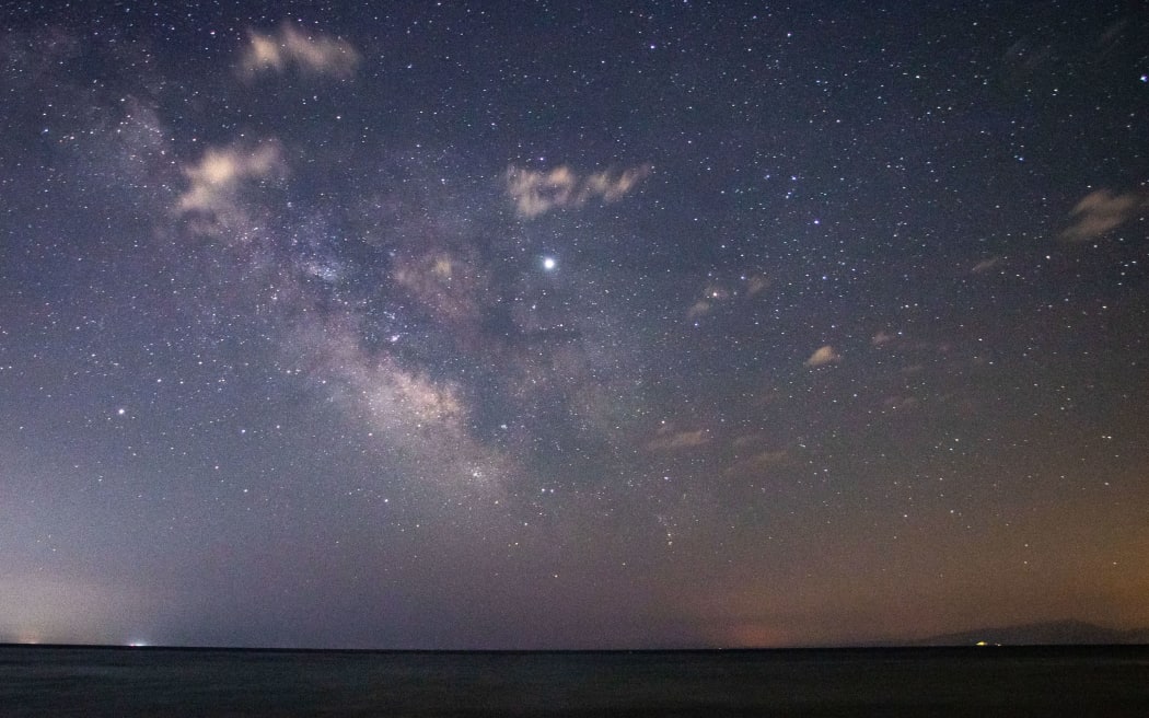 The Milky Way in Epanomi shipwreck beach near Thessaloniki in Greece. The water of the sea, Thermaikos Gulf, the shore of Epanomi and Kisavos mountain visible on the photo.