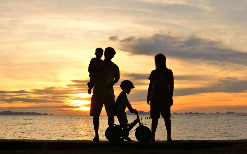 silhouette of family on the beach at dusk.