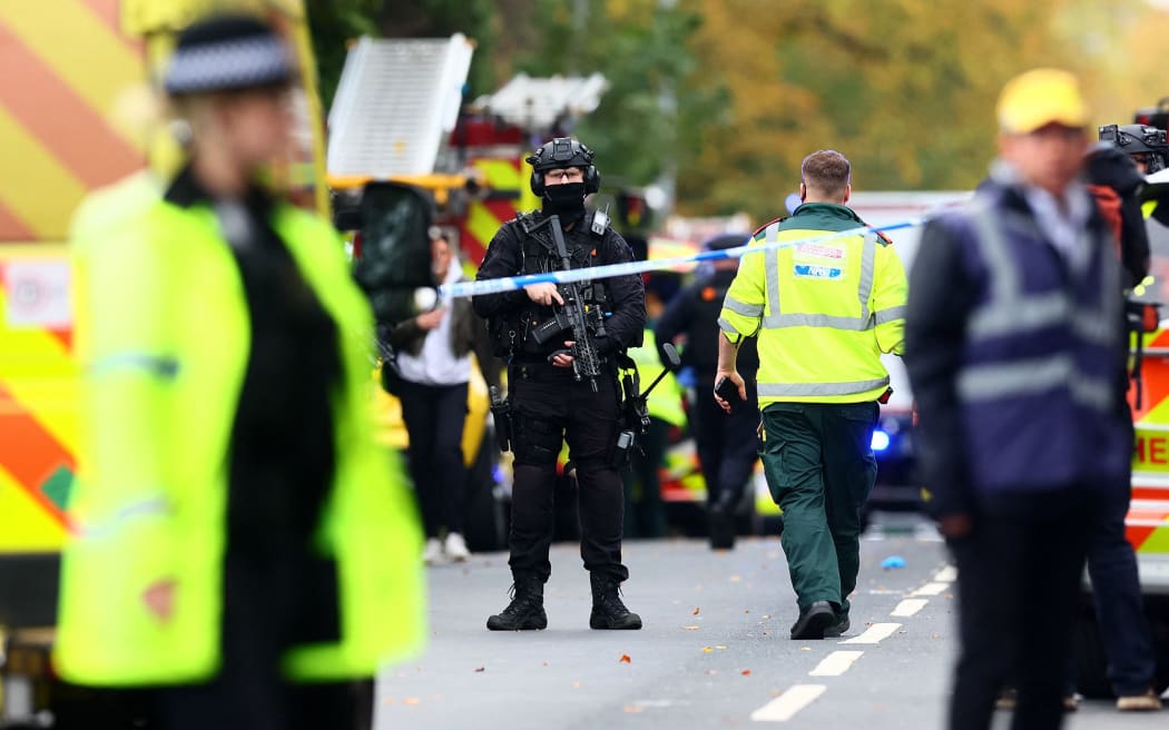 Armed police officers stand with their weapons inside a police cordon near Heaton Park Hebrew Congregation synagogue in Crumpsall, north Manchester, on October 2, following a stabbing and vehicle attack.