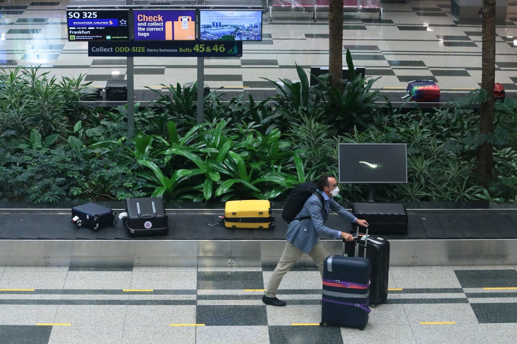A man wearing a mask collects his bag after arriving in Singapore on the first 'vaccinated lane' flight from Germany on 8 September.