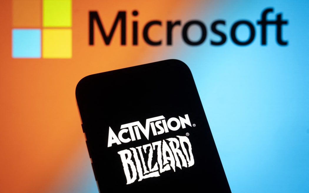 The Activision Blizzard logo is seen with a Microsoft logo in the background in this photo illustration on 13 July, 2023 in Warsaw, Poland.
