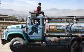 In this picture taken on April 27, 2025, an Afghan boy sits atop a potable water tanker on a hillside in Kabul. Kabulis will have to lug water in heavy jugs from wells or buy it from tankers -- which charge at least twice as much as the state-owned utility, with potable water even more pricy as the city struggles to combat an entrenched water crisis, in a country where 85 percent of the population lives on less than a dollar a day, according to the United Nations. (Photo by Wakil KOHSAR / AFP) / TO GO WITH: AFGHANISTAN-WATER-URBAN-PLANNING, REPORTAGE BY SUSANNAH WALDEN