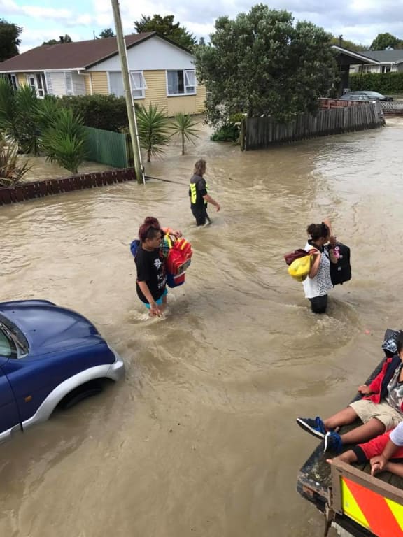 Residents in Edgecumbe carry belongings with them as they prepare to evacuate the town.