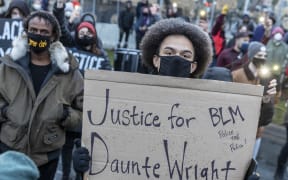 A protester holds a sign reading "Justice for Daunte Wright" during a rally outside the Brooklyn Center police station to protest the death of Daunte Wright who was shot and killed by a police officer in Brooklyn Center, Minnesota on 13 April 2021.