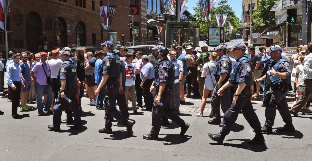 Police walk through Martin Place as spectators look on during a hostage siege.