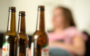 ILLUSTRATION - A girl sits behind empty beer bottles in Berlin, Germany, with a bottle of beer standing in the foreground, 28 May 2016. Alocohol and media addiciton is often a taboo issue for parents, often help of information centres is sought too late. Photo: Alexander Heinl/dpa (Photo by Alexander Heinl / DPA / dpa Picture-Alliance via AFP)