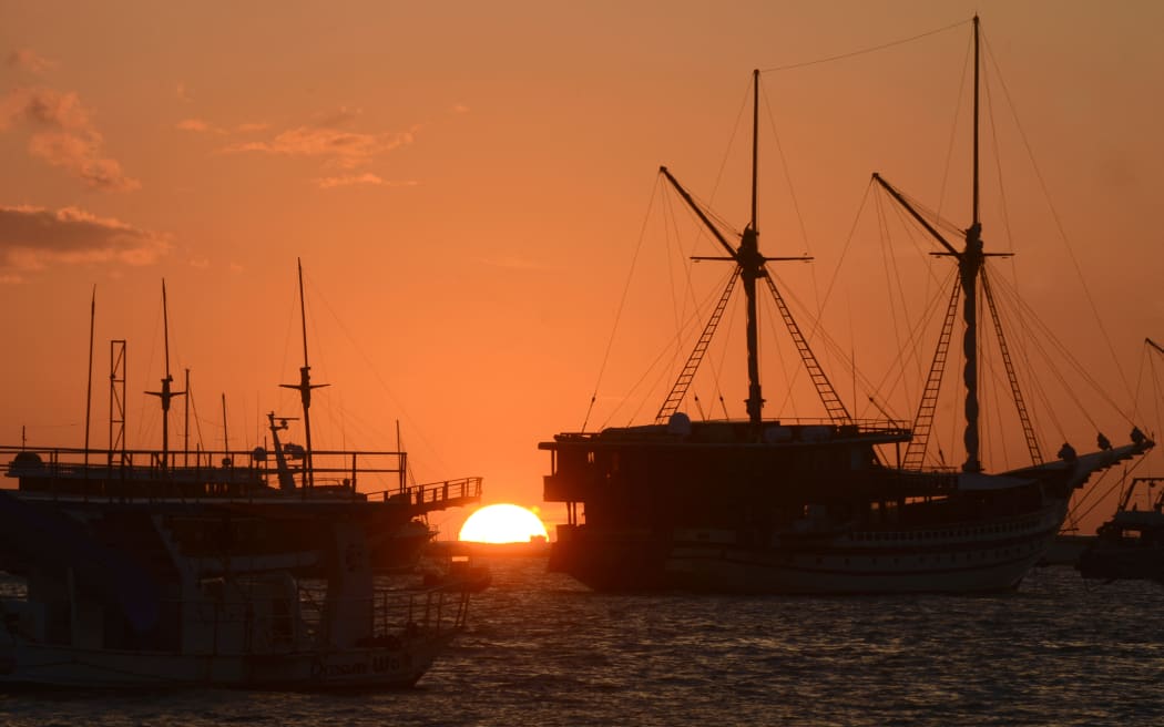 The sun rises behind tourist boats moored off a pier at Serangan island, near Denpasar on Indonesia's resort island of Bali on June 3, 2020. (Photo by SONNY TUMBELAKA / AFP)