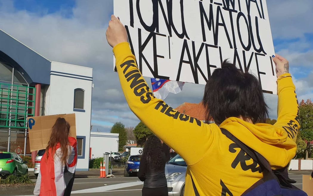 Woman in hoodie holding up a sign