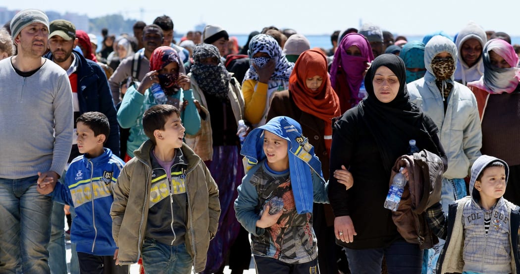 Rescued migrants walk along the quayside after disembarking from the Italian Navy vessel Bettica in the Sicilian harbour of Augusta on April 22, 2015 .