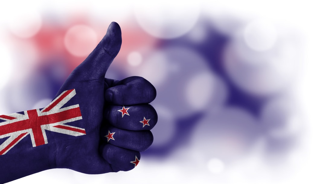 Flag of New Zealand drawn on a man's hand with a thumb up, on a blurry background with a good place for text