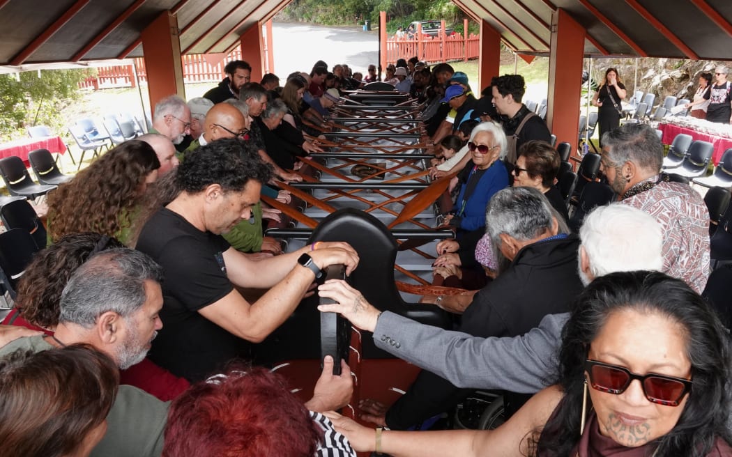 Members of Ngāti Rēhia and manuhiri [guests] place their hands on the waka during the blessing.