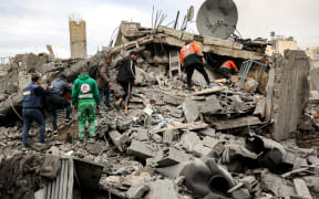 People and first responders inspect the rubble of a collapsed residential building that was hit by Israeli bombardment in the Saraya area in al-Rimal in central Gaza City on January 4, 2025 amid the ongoing war in the Palestinian territory between Israel and Hamas. (Photo by Omar AL-QATTAA / AFP)