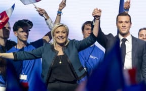 France, Paris, 2024-06-02, Lead candidate of the French far-right party Rassemblement national (RN) Jordan Bardella (R) and RN parliamentary group chair Marine Le Pen (L) hold hands on stage at the Dome in Paris during a campaign meeting ahead of the forthcoming European Parliament elections, Photograph by Serge Tenani / Hans Lucas, 
France, Paris, 2024-06-02, Le candidat principal du parti d extreme droite francais Rassemblement national (RN) Jordan Bardella (R) et la presidente du groupe parlementaire du RN Marine Le Pen (L) se tiennent la main sur la scene du Dome de Paris lors d une reunion de campagne avant les prochaines elections du Parlement europeen, Photographie de Serge Tenani / Hans Lucas. (Photo by Serge Tenani / Hans Lucas / Hans Lucas via AFP)