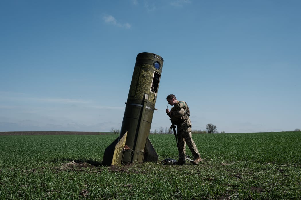 A Ukrainian serviceman looks at a Russian ballistic missile's booster stage that fell in a field in Bohodarove, eastern Ukraine, on April 25, 2022.