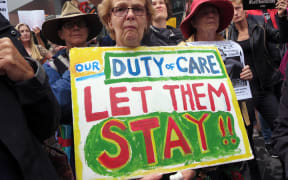 People hold up placards at a protest outside an immigration office in Sydney on February 4, 2016.