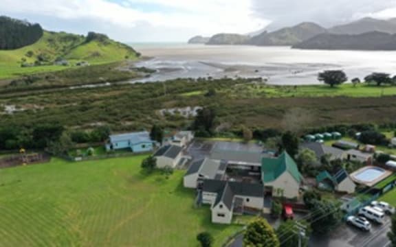A cluster of Colville School buildings are visible in a drone shot that shows a small stretch of mangroves next to the school and then the sea close by.