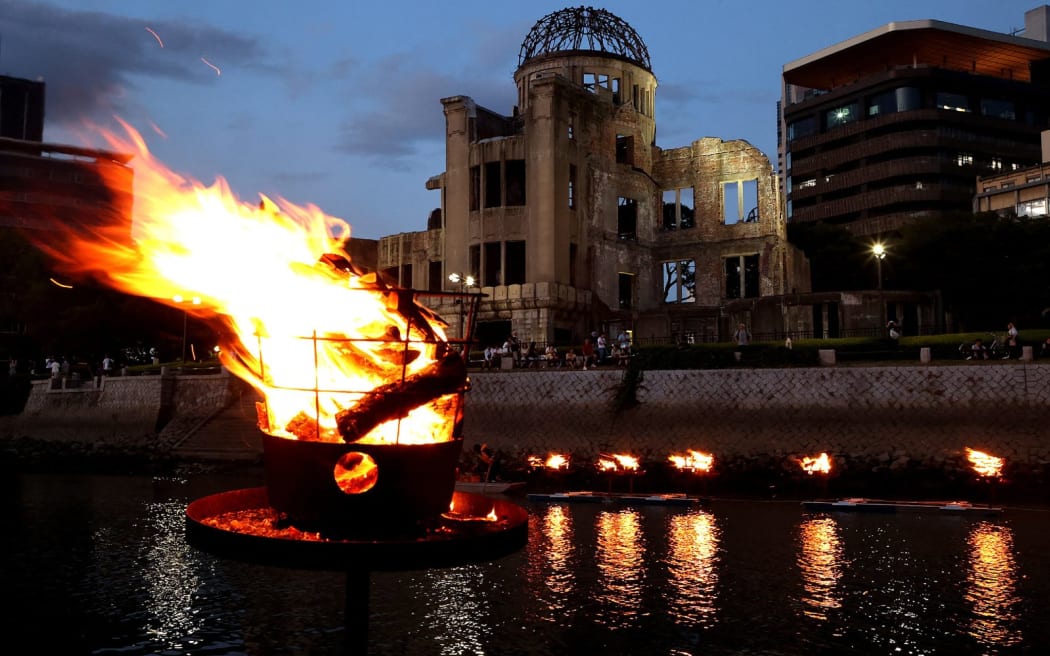 Lanterns are lit and placed on the Motoyasu river by the Atomic Bomb Dome (behind) in remembrance of the victims in Hiroshima on August 5, 2023, on the eve before ceremonies to mark the 78th anniversary of the world's first atomic bomb attack. (Photo by JIJI Press / AFP) / Japan OUT