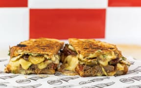 A toasted sandwich with meatloaf and cheese.