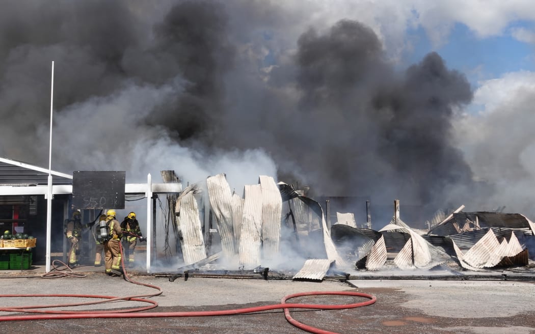 Firefighters from across Northland battle to contain the tyre shop blaze. Photo: RNZ / Peter de Graaf