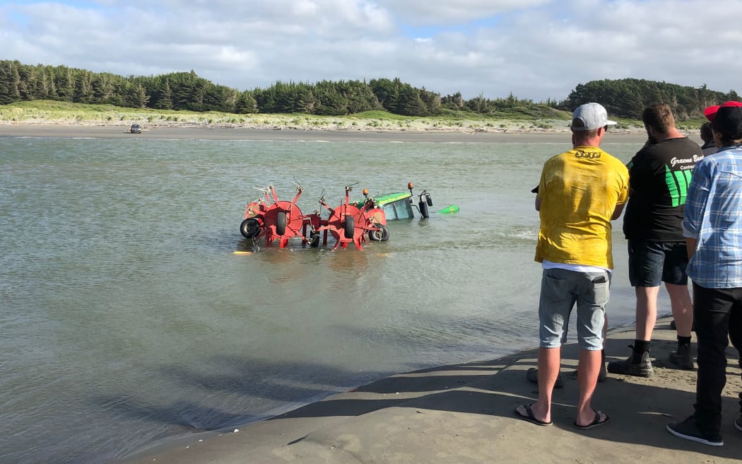 A tractor and hay baler stuck in the Manawatu River near Foxton Beach.