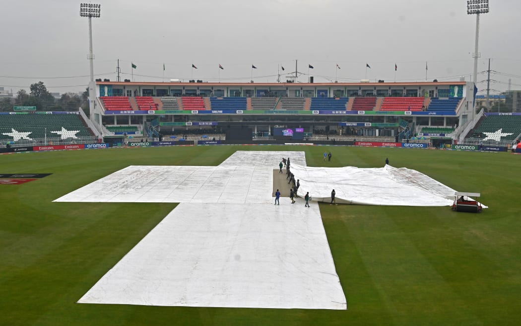 Groundsmen cover the pitch as it rains before the start of the ICC Champions Trophy match between Australia and South Africa in Rawalpindi, 2025.