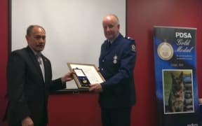 Senior Constable Lamb receives the PDSA gold medal for Gage.