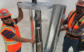 Workers installing an earthquake energy absorbing damper within the foundation of Casa Adelante. It was developed by Professor Geoffrey Rodgers from the University of Canterbury.
