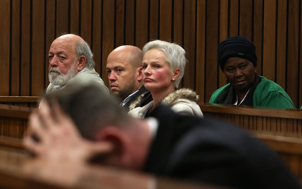 South African Paralympian Oscar Pistorius (Foreground) holds his head in his hands as members of Reeva Steenkamp's family including her father Barry Steenkamp(L), looks on during his resentencing hearing.