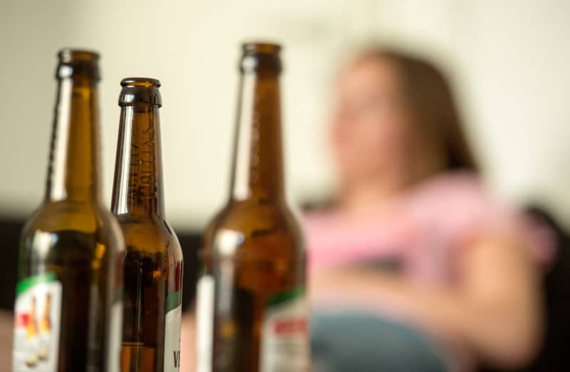 ILLUSTRATION - A girl sits behind empty beer bottles in Berlin, Germany, with a bottle of beer standing in the foreground, 28 May 2016. Alocohol and media addiciton is often a taboo issue for parents, often help of information centres is sought too late. Photo: Alexander Heinl/dpa (Photo by Alexander Heinl / DPA / dpa Picture-Alliance via AFP)