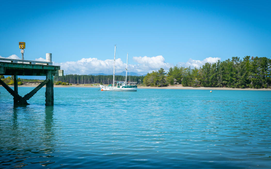 Wharf at Mapua with slopp moored in channel of Waimea Estuary on Tasman Bay in South Island New Zealand.