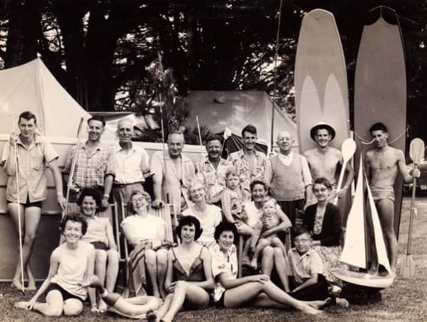 A group of smiling people with tents behind.