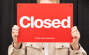 Man holding sign saying 'closed to harassment'